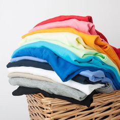 a wicker basket filled with different colored shirts