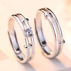 two silver rings with a diamond on the side and one has a white topaz