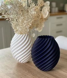 two white and blue vases sitting on top of a wooden table next to each other