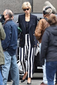 a woman in black and white striped pants is walking down the street with other people