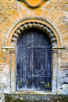 an old wooden door with iron bars on the front and side of a brick building