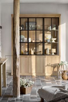 a large wooden cabinet with glass doors and shelves in the center, surrounded by vases