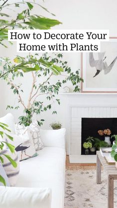 a living room filled with white furniture and lots of greenery on the wall next to a fire place