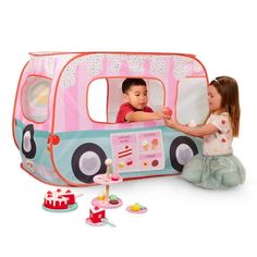 two young children playing with a toy bus shaped like a camper van and other toys