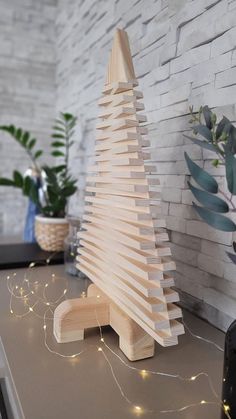 a wooden christmas tree sitting on top of a table next to a potted plant