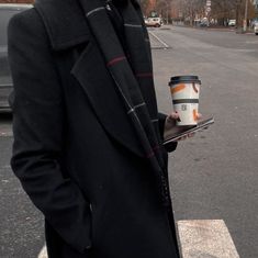 a man holding a cup of coffee while standing in the street