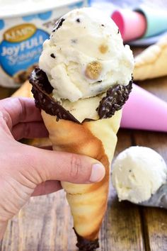 someone is holding an ice cream cone with chocolate and vanilla on top, while the cones are in front of them