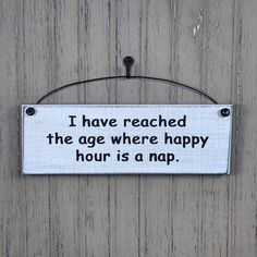 a sign that says i have reached the age where happy hour is a nap hanging on a wall