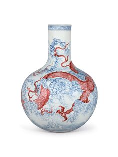 a blue and white vase with red dragon designs on the bottom, sitting against a white background