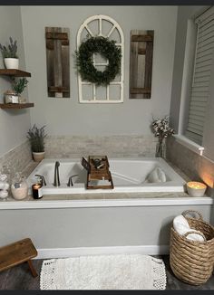 a white bath tub sitting in a bathroom next to a wooden shelf with candles on it