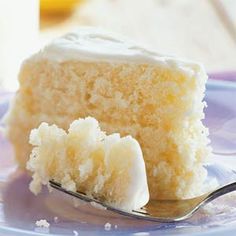 a piece of cake with white frosting on a blue plate next to a fork