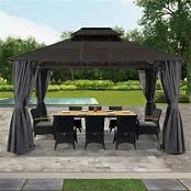 an outdoor dining area with a table and chairs under a gazebo in the grass