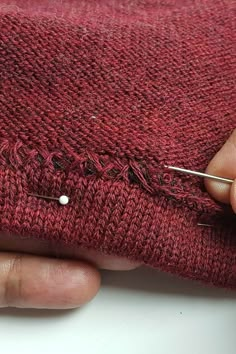 someone is stitching the stitches on a red sweater