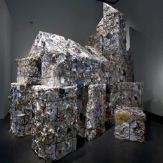 several stacks of garbage stacked on top of each other in an art gallery with white walls and black floors