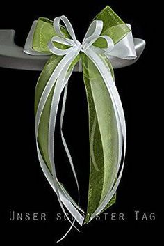 a green bow with white ribbon on a black background