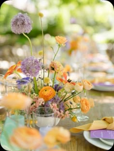 an arrangement of flowers in a vase on top of a table with plates and napkins