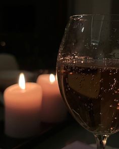 a glass filled with liquid next to candles