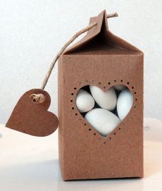 a cardboard box with eggs in it and a heart hanging from the top, on a table