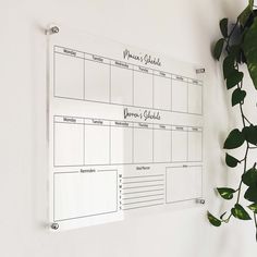 a white board mounted to the side of a wall next to a potted plant