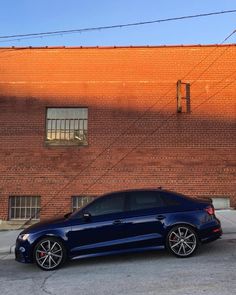 a blue car parked in front of a brick building