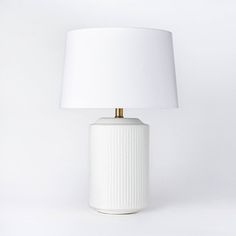 a white ceramic lamp with a gold metal base and a white shade on the top