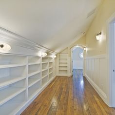 an empty room with white shelving and wood flooring in the center is shown