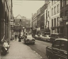 an old black and white photo of people walking down the street