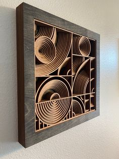 an art piece made out of wood with circles and spirals on the wall above it