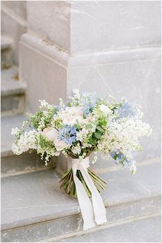 a bouquet of white and blue flowers sitting on the steps