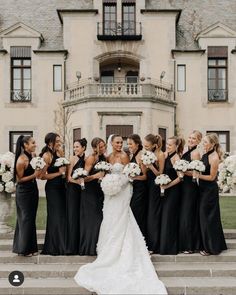 a bride and her bridal party in front of a large building with white flowers