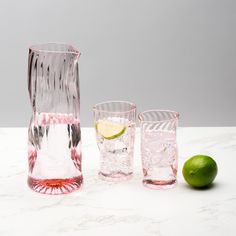 three glasses and one lime on a marble table