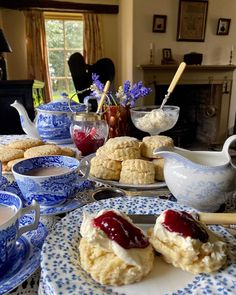 a table topped with blue and white plates filled with pastries next to tea cups