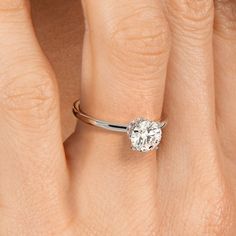 a woman's hand with a diamond ring on her left hand and the other hand holding an engagement ring