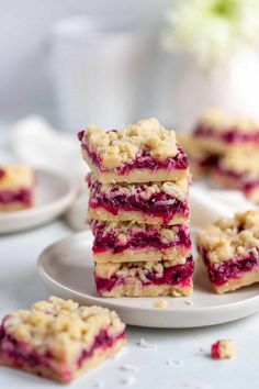 raspberry crumb bars stacked on top of each other in front of white plates