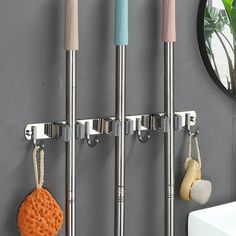 three metal hooks holding two umbrellas and some other items in front of a mirror