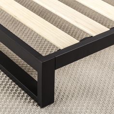 a wooden bed frame sitting on top of a carpeted floor next to a rug