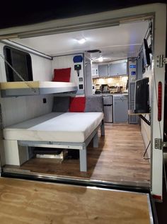 the interior of a camper trailer with bunk beds and kitchen area in it's back