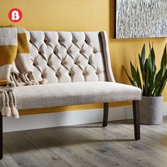 a white couch sitting on top of a wooden floor next to a potted plant