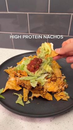 a black plate topped with nachos covered in lettuce