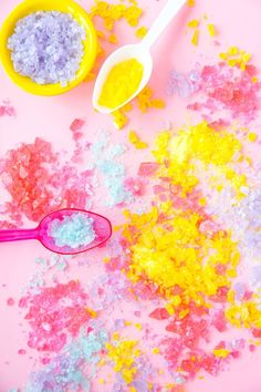 two spoons and some colored powder on a pink surface with other things to make it look like they are made out of rice