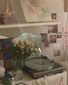 a record player sitting on top of a table next to a vase filled with flowers