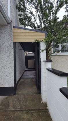 an alley way leading to a building with a tree in the corner and grass growing on the ground