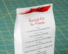 a white paper bag with a red ribbon on it and the words survival kit for friends