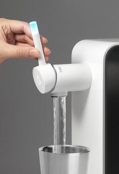 a person is holding an electric toothbrush in front of a water dispenser