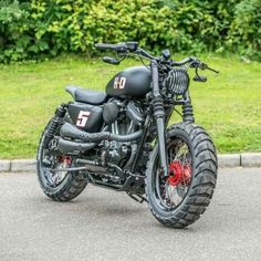 a black motorcycle parked on the street in front of some grass and bushes with trees behind it