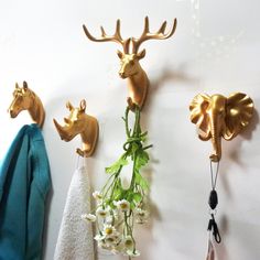 three brass deer head hooks on the wall with flowers and towels hanging from it's sides