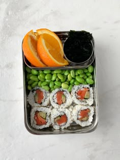 a bento box filled with sushi, peas and orange slices on top of it