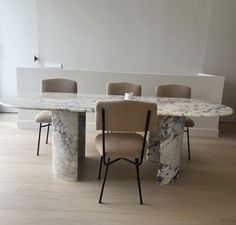 a marble dining table with four chairs around it