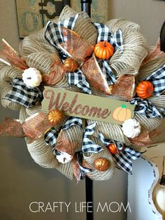 a welcome fall wreath with pumpkins, burlocks and ribbon on it that says welcome crafty life mom