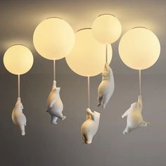 several white lamps hanging from the ceiling with animals on them and balls in the air